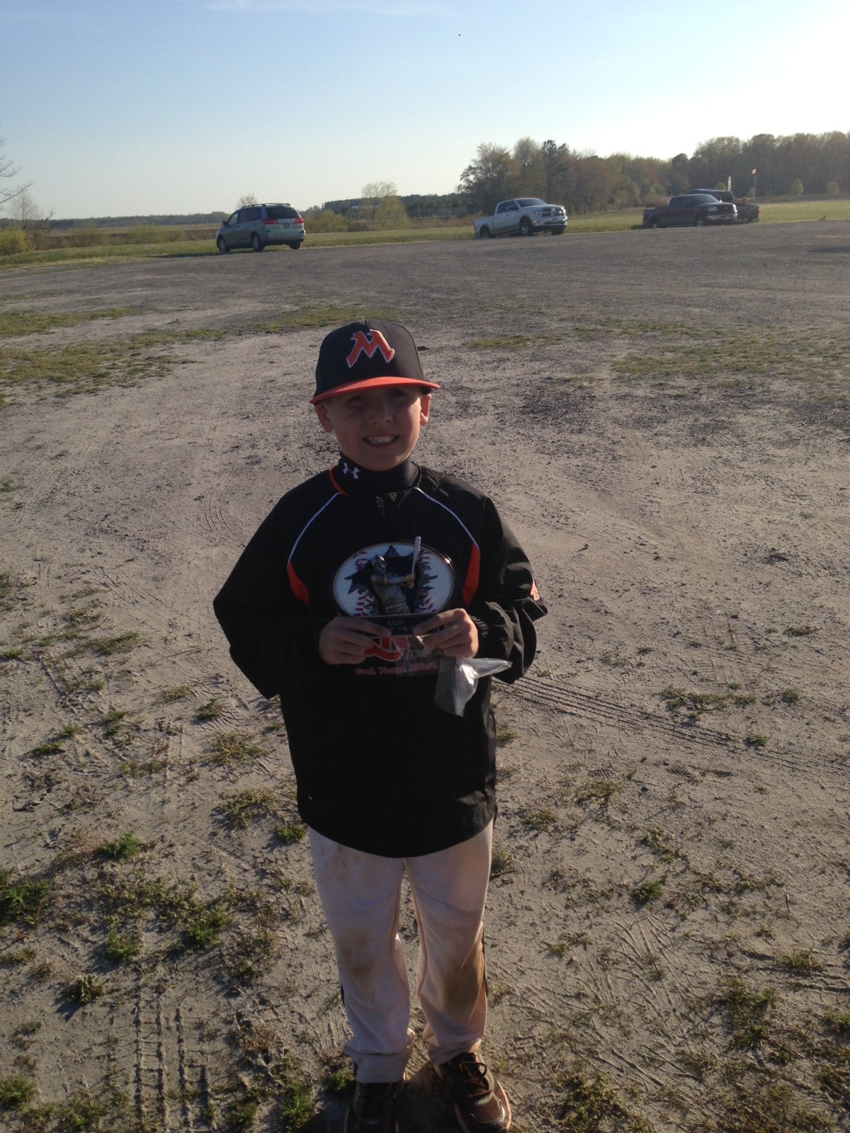 A young player smiling and holding an MVP award plaque after a game